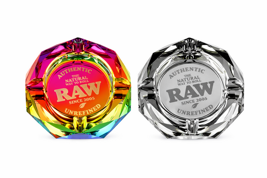 Two RAW branded glass ashtrays, one rainbow-colored and one clear on a pure white background.