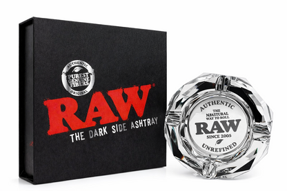 RAW Limited Edition Glass Ashtray displayed beside its black box packaging on a pure white background, featuring “RAW The Dark Side Ashtray” branding and engraved authentic RAW logo details.