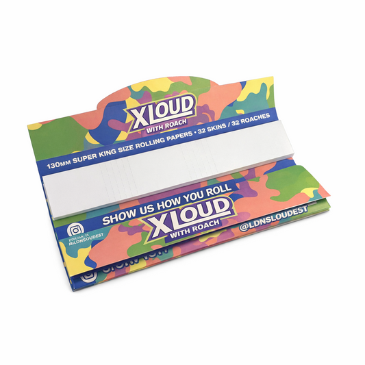 Open pack of XLoud Extra Long Rolling Papers with Tips displayed on a pure white background. The pack features a colourful camouflage design in green, pink, yellow, and blue, with the XLoud logo and “WITH ROACH” printed on both top and bottom sections. Inside, extra‑long white rolling papers are neatly stacked, showing the included perforated tips on the right side.